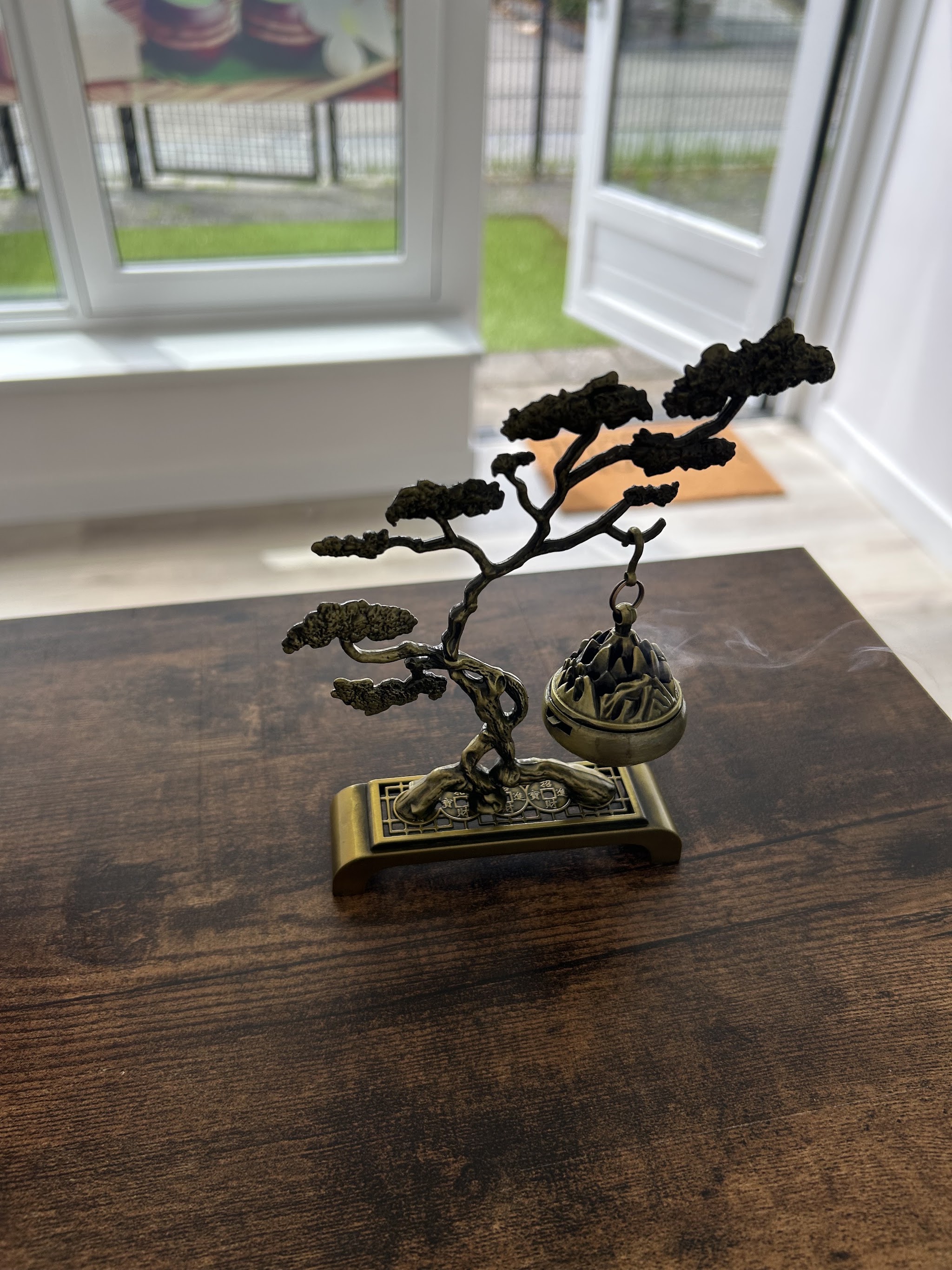 Een bronzen bonsai-wierookbrander op de donkere houten tafel