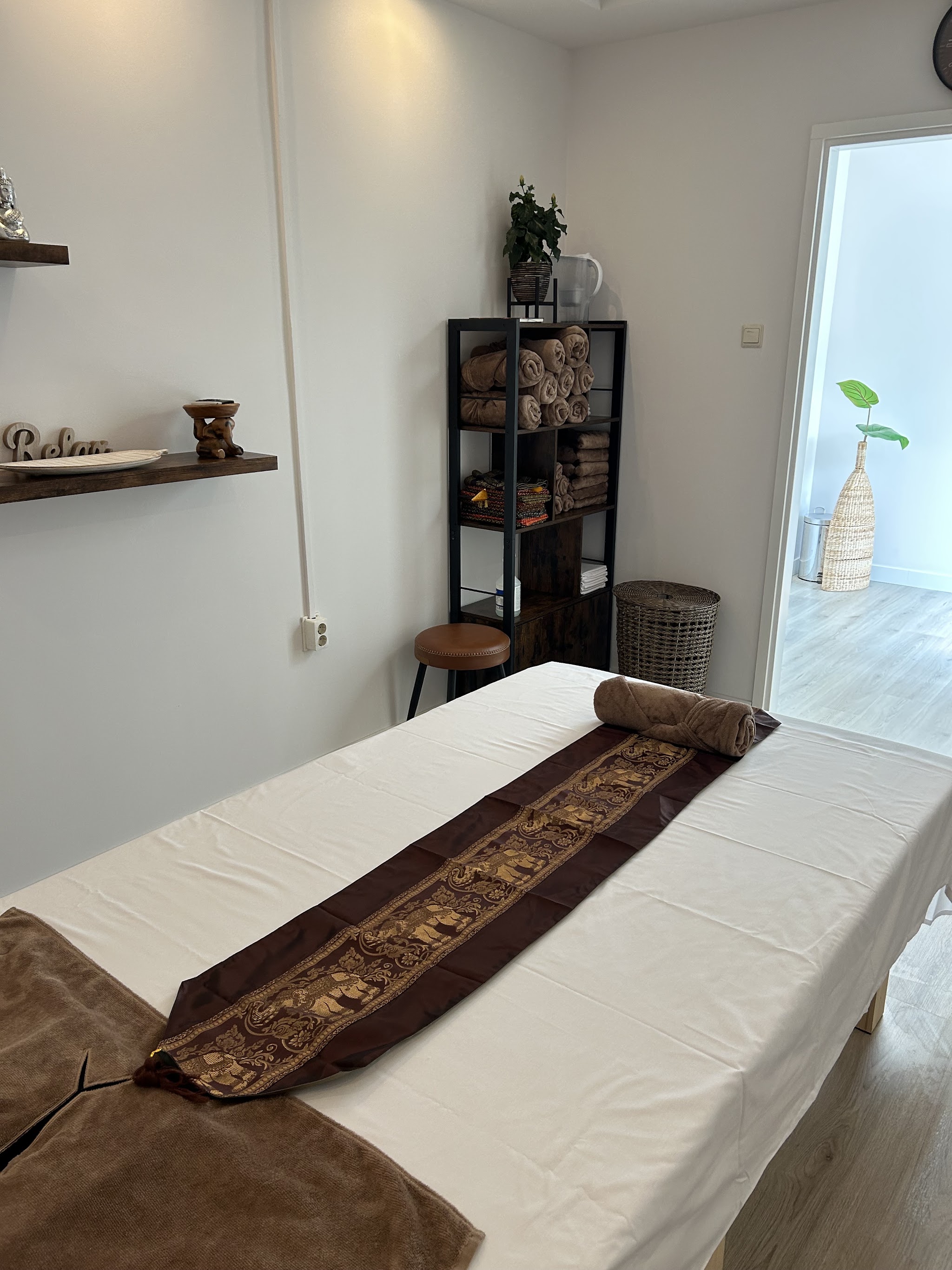 Behandelkamer met massagetafel, handdoeken in het rek en een kruk